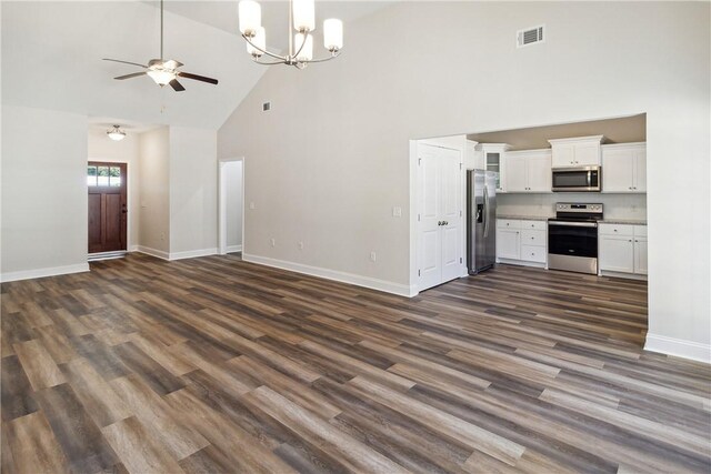 unfurnished living room with high vaulted ceiling, dark wood-type flooring, and ceiling fan with notable chandelier