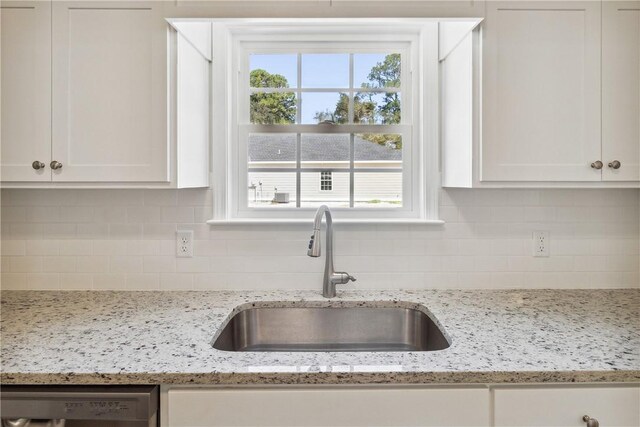 kitchen featuring light stone counters, white cabinetry, sink, and tasteful backsplash