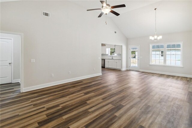 unfurnished living room with ceiling fan with notable chandelier, high vaulted ceiling, and dark hardwood / wood-style floors