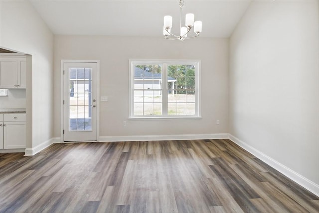 unfurnished dining area with a chandelier and dark wood-type flooring