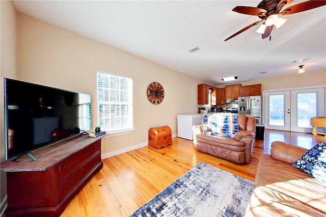 living room with french doors, ceiling fan, light hardwood / wood-style floors, and a wealth of natural light