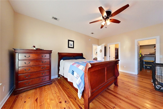 bedroom with a spacious closet, ceiling fan, and light hardwood / wood-style floors