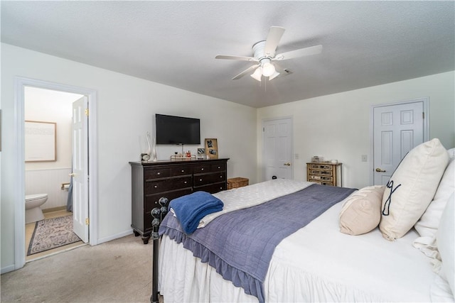 bedroom featuring ceiling fan, baseboards, connected bathroom, and light colored carpet