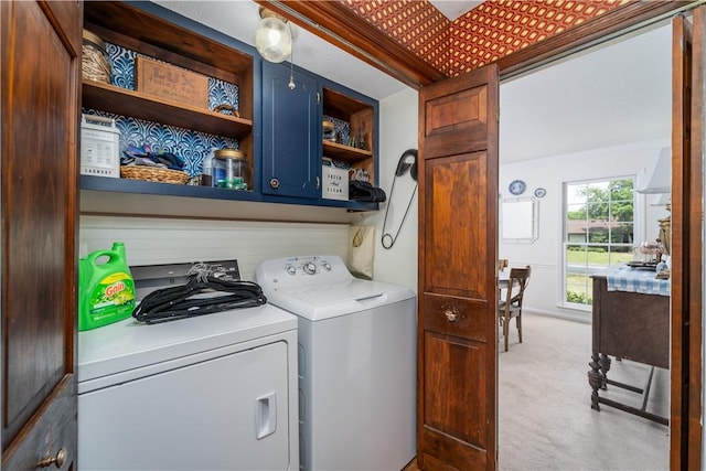 clothes washing area with washing machine and clothes dryer, light colored carpet, and cabinet space