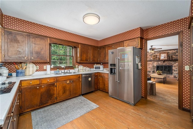 kitchen with light wood-type flooring, light countertops, a sink, and appliances with stainless steel finishes