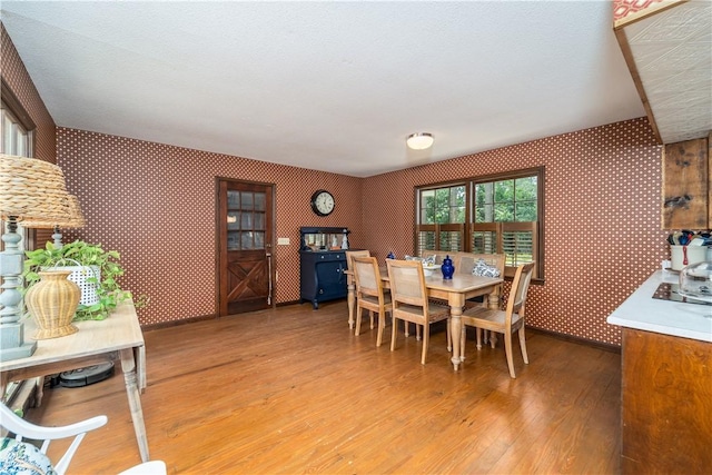 dining room with wallpapered walls and light wood-type flooring