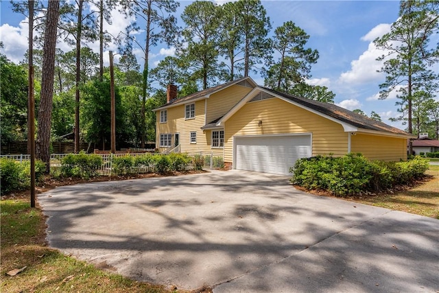 view of front of house featuring a chimney, aphalt driveway, fence, and a garage
