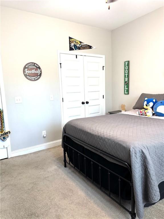 bedroom featuring baseboards, light carpet, and a closet