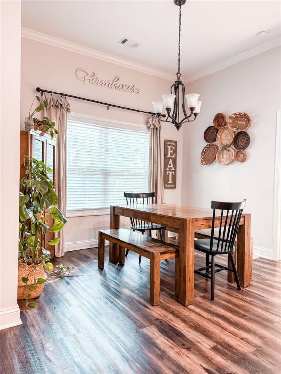 dining space featuring visible vents, crown molding, and wood finished floors