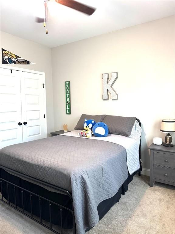 bedroom featuring light carpet, baseboards, a closet, and a ceiling fan