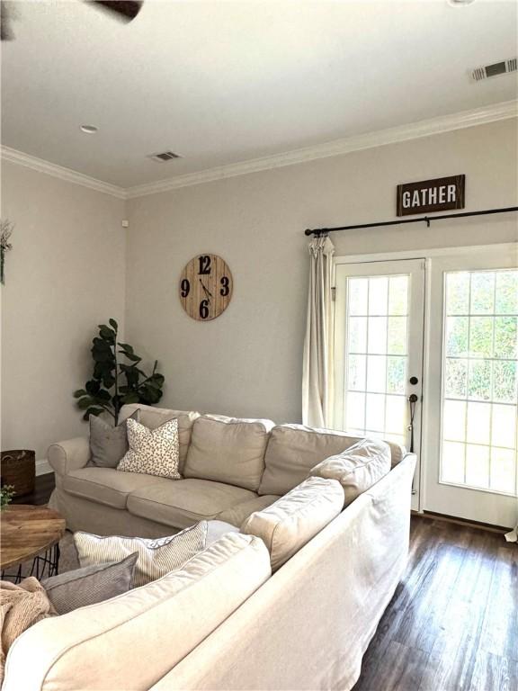 living area featuring dark wood finished floors, crown molding, and visible vents