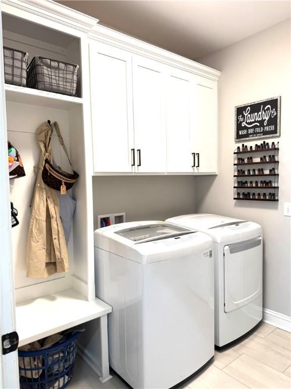 washroom featuring baseboards, cabinet space, and separate washer and dryer