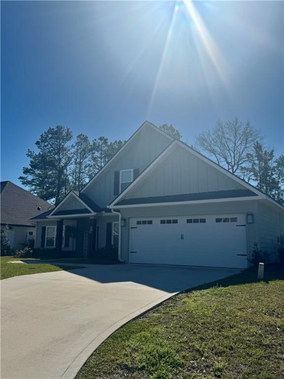 craftsman house with concrete driveway, an attached garage, board and batten siding, and a front lawn