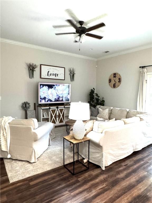 living area with crown molding, wood finished floors, visible vents, and ceiling fan