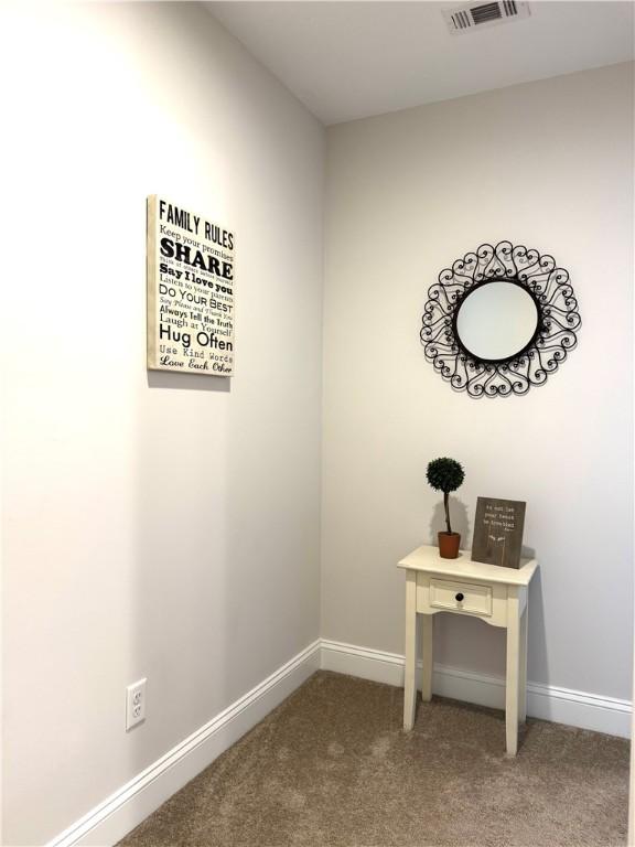 interior space featuring visible vents, baseboards, and carpet