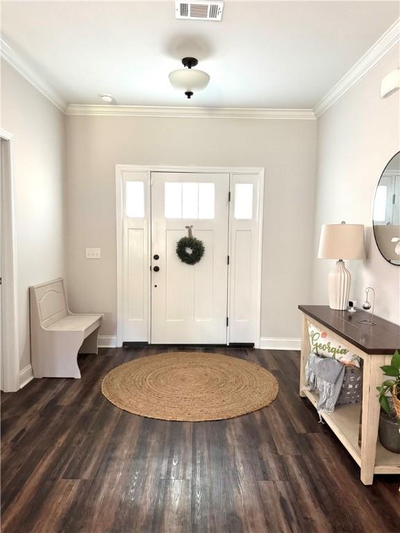 foyer entrance featuring dark wood finished floors, visible vents, baseboards, and ornamental molding