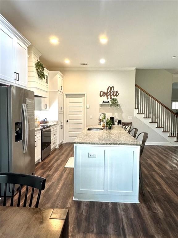 kitchen with light stone counters, dark wood-style flooring, a sink, stainless steel appliances, and white cabinets