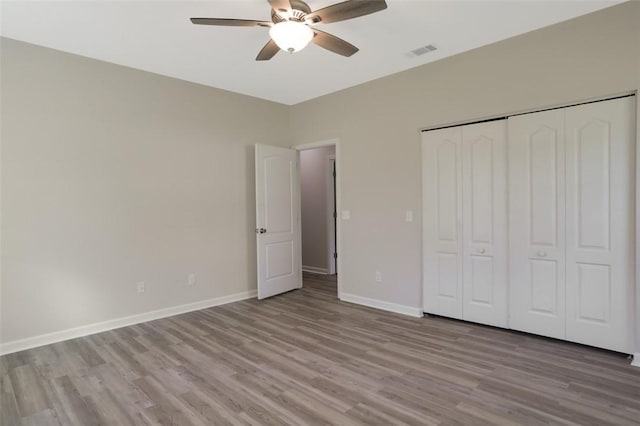 unfurnished bedroom featuring ceiling fan, light wood-type flooring, and a closet