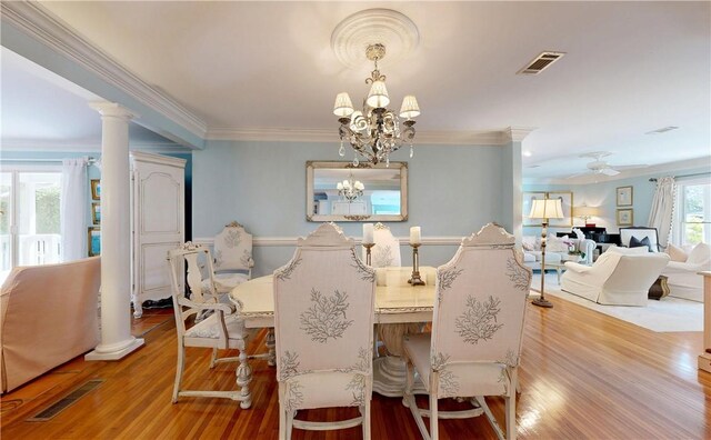 231 Magnolia Ave, Saint Simons Island, GA 31522 - dining room featuring wood finished floors, a chandelier, ornamental molding, ceiling fan, and ornate columns