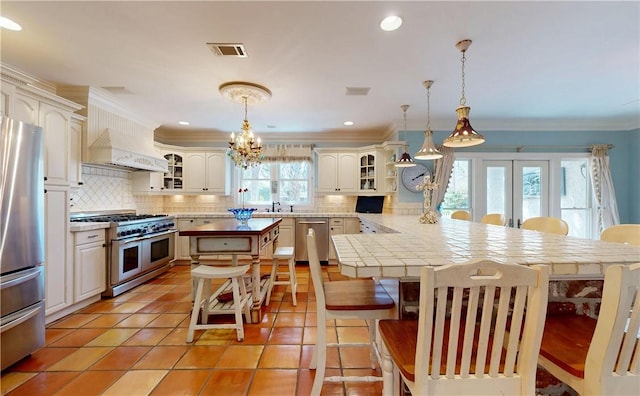 231 Magnolia Ave, Saint Simons Island, GA 31522 - kitchen with stainless steel appliances, a kitchen breakfast bar, a peninsula, backsplash, and crown molding