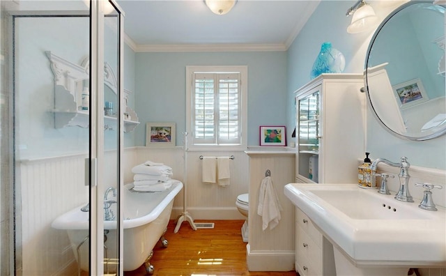 231 Magnolia Ave, Saint Simons Island, GA 31522 - full bath with a wainscoted wall, wood finished floors, ornamental molding, a freestanding tub, and toilet