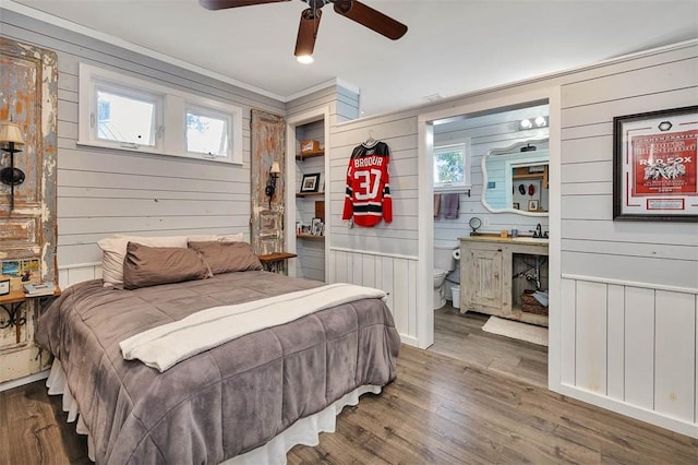 bedroom featuring wood walls, crown molding, ceiling fan, and wood-type flooring