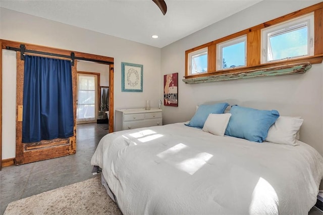 bedroom featuring ceiling fan, a barn door, and multiple windows