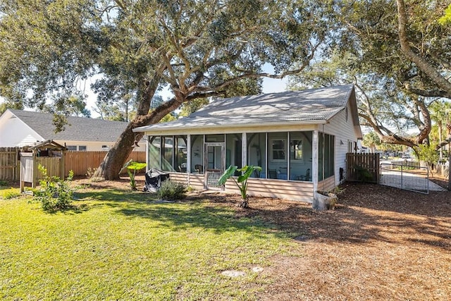 rear view of property featuring a sunroom and a yard