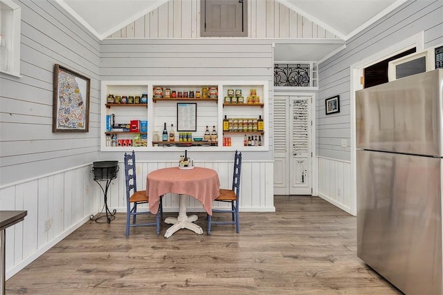 interior space with high vaulted ceiling, light hardwood / wood-style flooring, and wooden walls