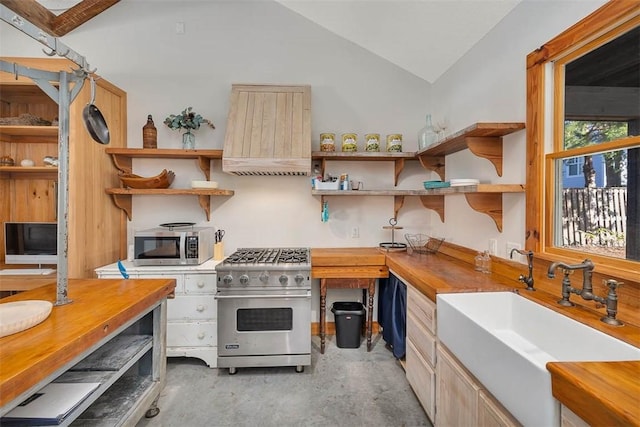 kitchen featuring premium range hood, sink, vaulted ceiling, appliances with stainless steel finishes, and butcher block countertops