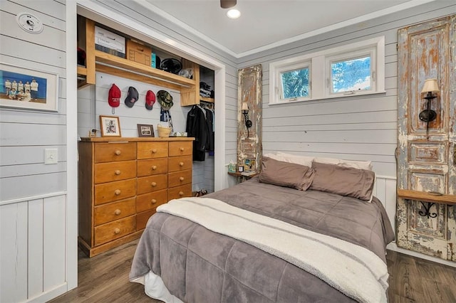 bedroom with dark hardwood / wood-style floors, a closet, and wood walls