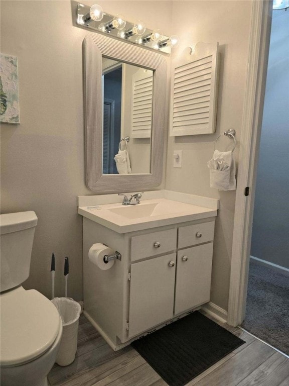 bathroom with hardwood / wood-style floors, vanity, and toilet