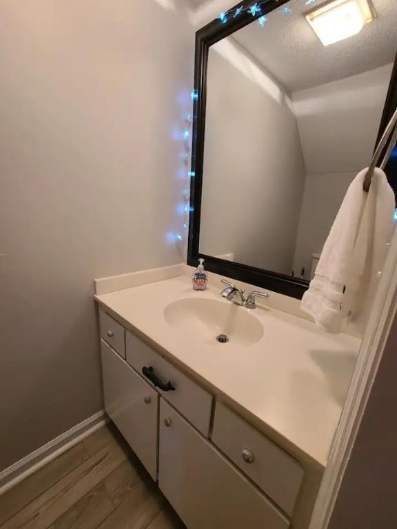 bathroom featuring hardwood / wood-style flooring, vanity, and a textured ceiling