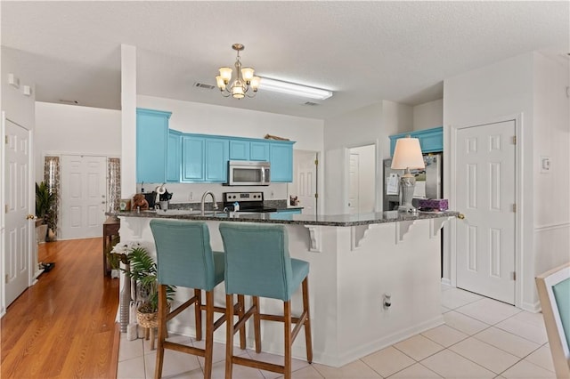 114 Shell Pointe Dr, Brunswick, GA 31525 - kitchen with appliances with stainless steel finishes, a textured ceiling, blue cabinets, a notable chandelier, and light hardwood / wood-style floors