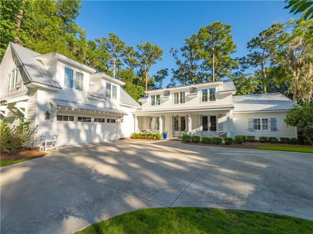 904 Champney, Saint Simons Island, GA 31522 - view of front of property featuring driveway, a porch, a garage, and a metal roof