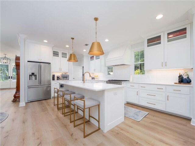 904 Champney, Saint Simons Island, GA 31522 - kitchen with stainless steel fridge, custom range hood, light countertops, backsplash, and light wood-type flooring
