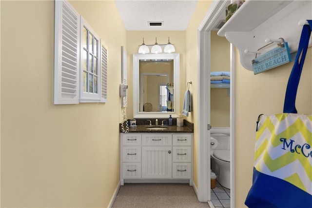 bathroom featuring tile patterned flooring, vanity, toilet, and a textured ceiling