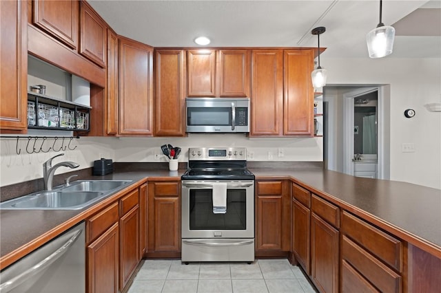 kitchen featuring appliances with stainless steel finishes, a sink, light tile patterned floors, and dark countertops