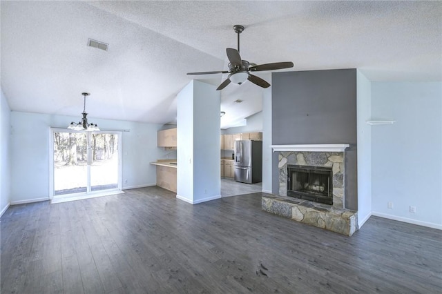 unfurnished living room with a textured ceiling, vaulted ceiling, dark hardwood / wood-style flooring, ceiling fan with notable chandelier, and a fireplace