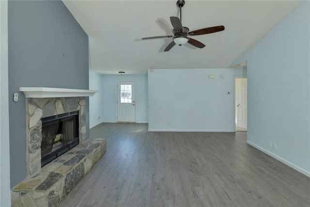 unfurnished living room featuring ceiling fan, hardwood / wood-style flooring, and a stone fireplace