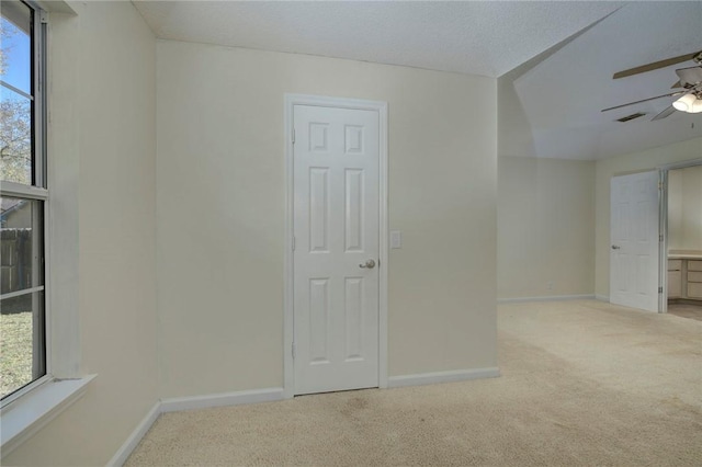 carpeted empty room featuring lofted ceiling, a textured ceiling, ceiling fan, and a healthy amount of sunlight