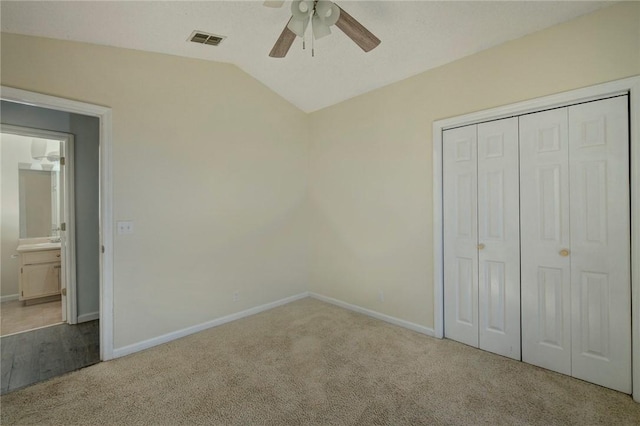 unfurnished bedroom with ceiling fan, light colored carpet, a closet, and lofted ceiling