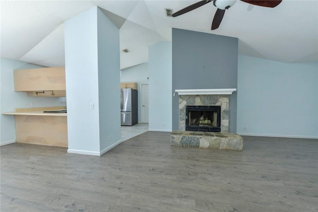 unfurnished living room with lofted ceiling, a fireplace, light wood-type flooring, and ceiling fan