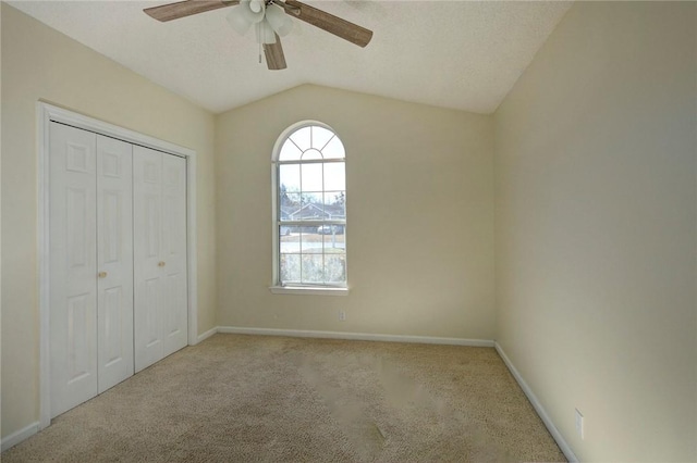 unfurnished bedroom with lofted ceiling, ceiling fan, a closet, and light carpet