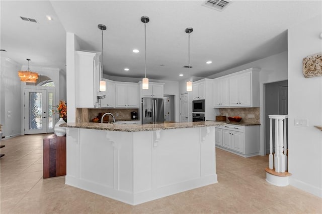 kitchen with stainless steel fridge, a kitchen breakfast bar, light stone counters, white cabinets, and built in microwave