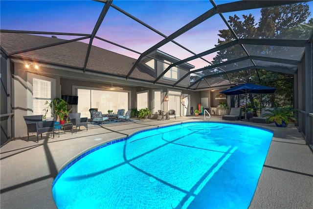 pool at dusk featuring a lanai and a patio area