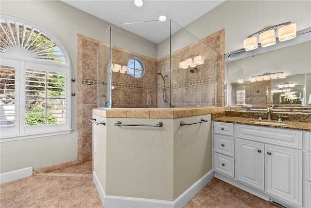 bathroom featuring tile patterned flooring, vanity, tiled shower, and a wealth of natural light