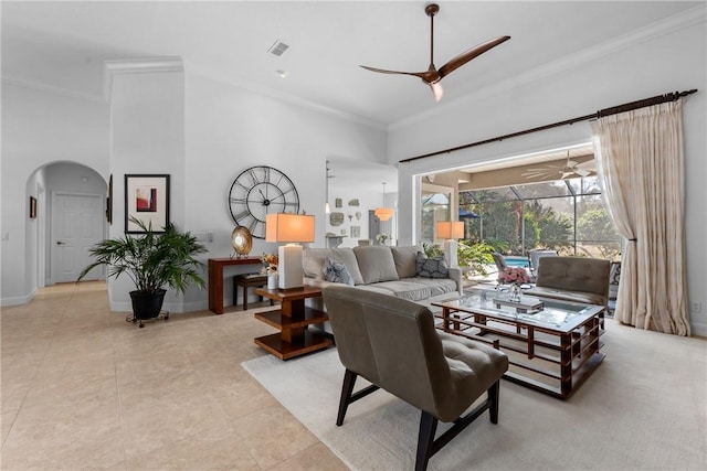 tiled living room featuring ceiling fan, ornamental molding, and a high ceiling