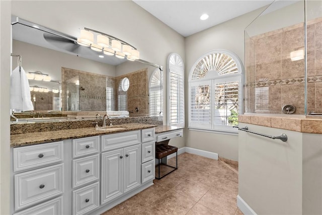 bathroom with tiled shower, vanity, and tile patterned flooring