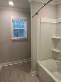 bathroom with hardwood / wood-style flooring, shower / bathtub combination, and ornamental molding